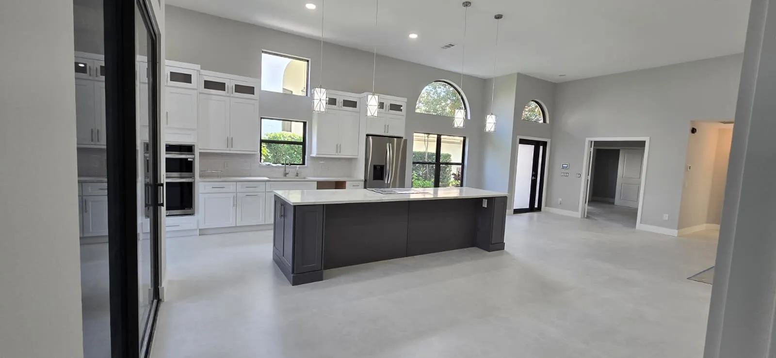 Open kitchen with charcoal island, pendant lights and white cabinetry