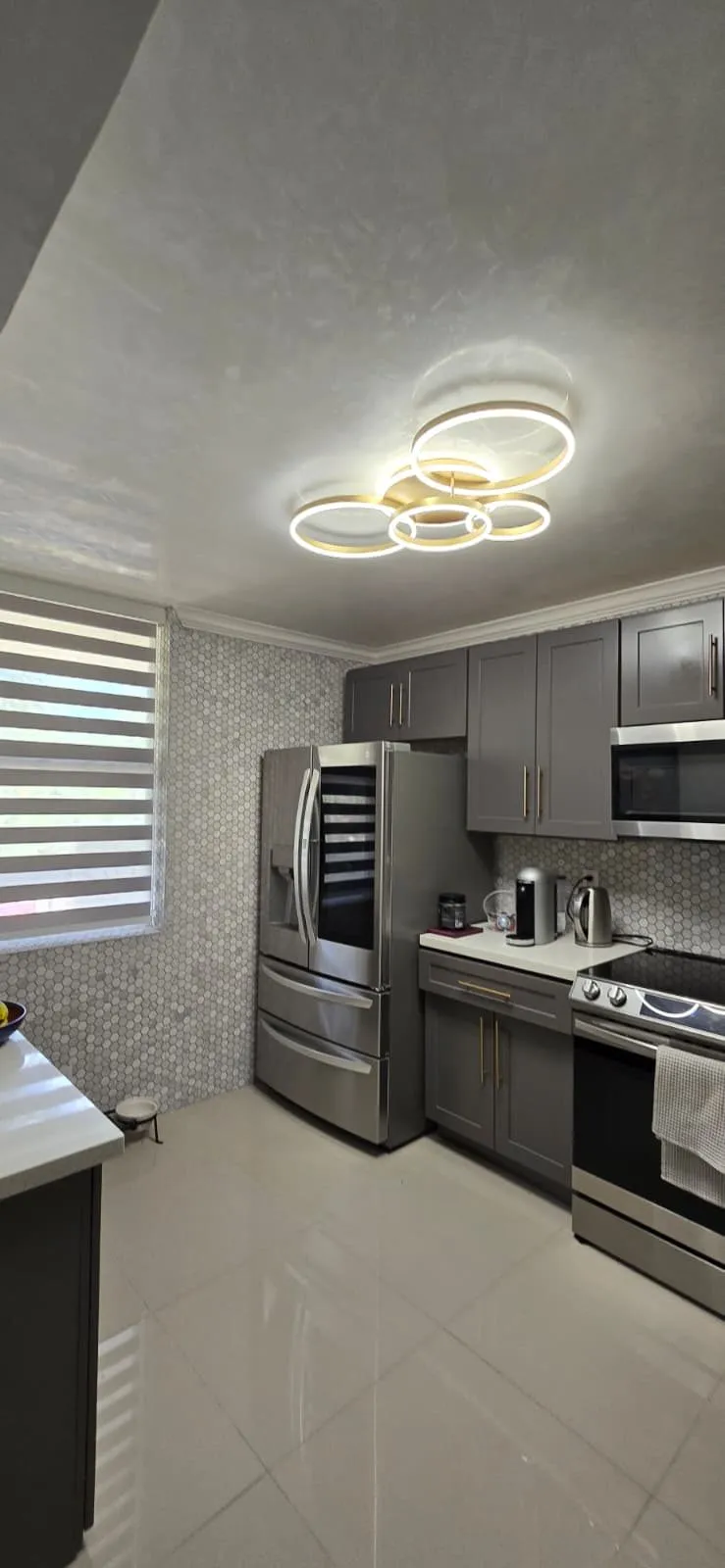Gray shaker kitchen with gold hardware and hexagon tile backsplash