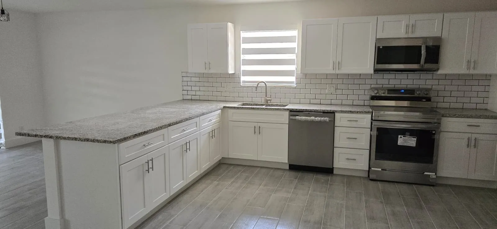 L-shaped white shaker kitchen with light granite