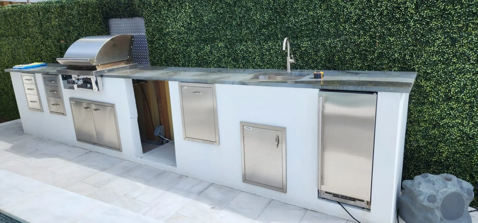 Outdoor kitchen in white stucco with stainless grill and storage doors